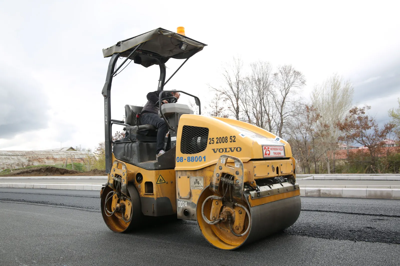 Compacteur sur une route de campagne fraîchement enrobée
